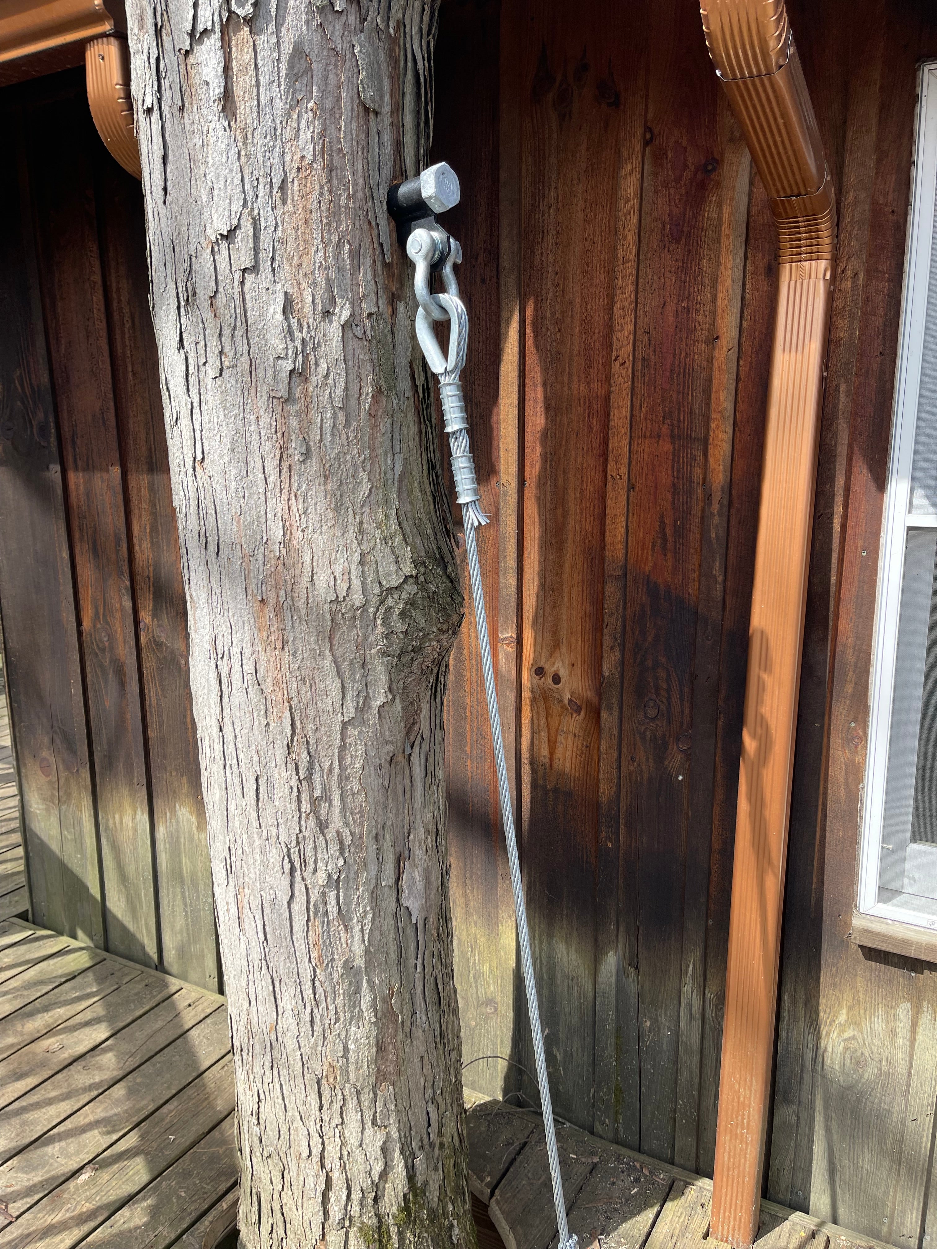 Wooden surface with a metal bracket and rope attached, possibly on a wooden structure.