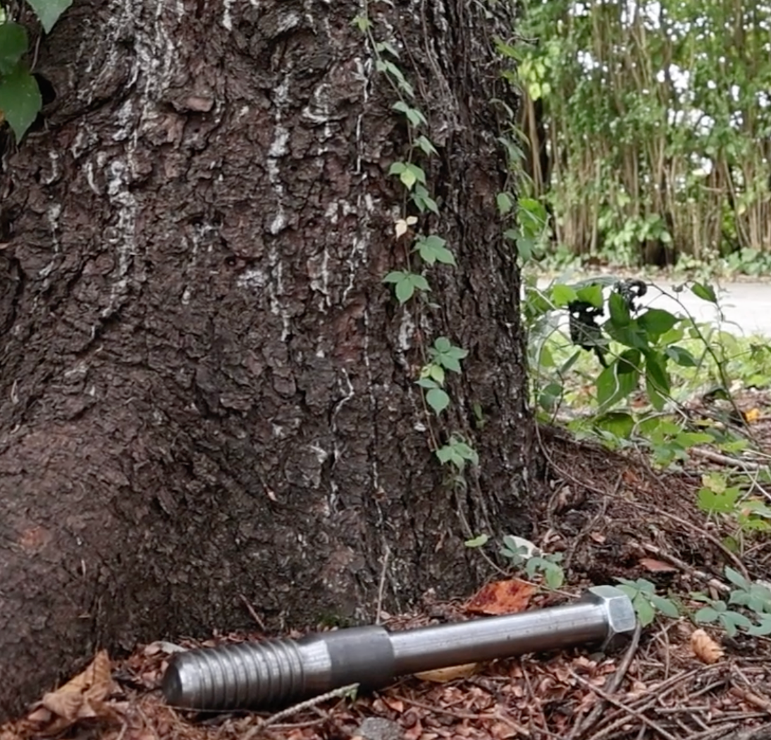 treehouse attachment bolt on the ground next to a tree